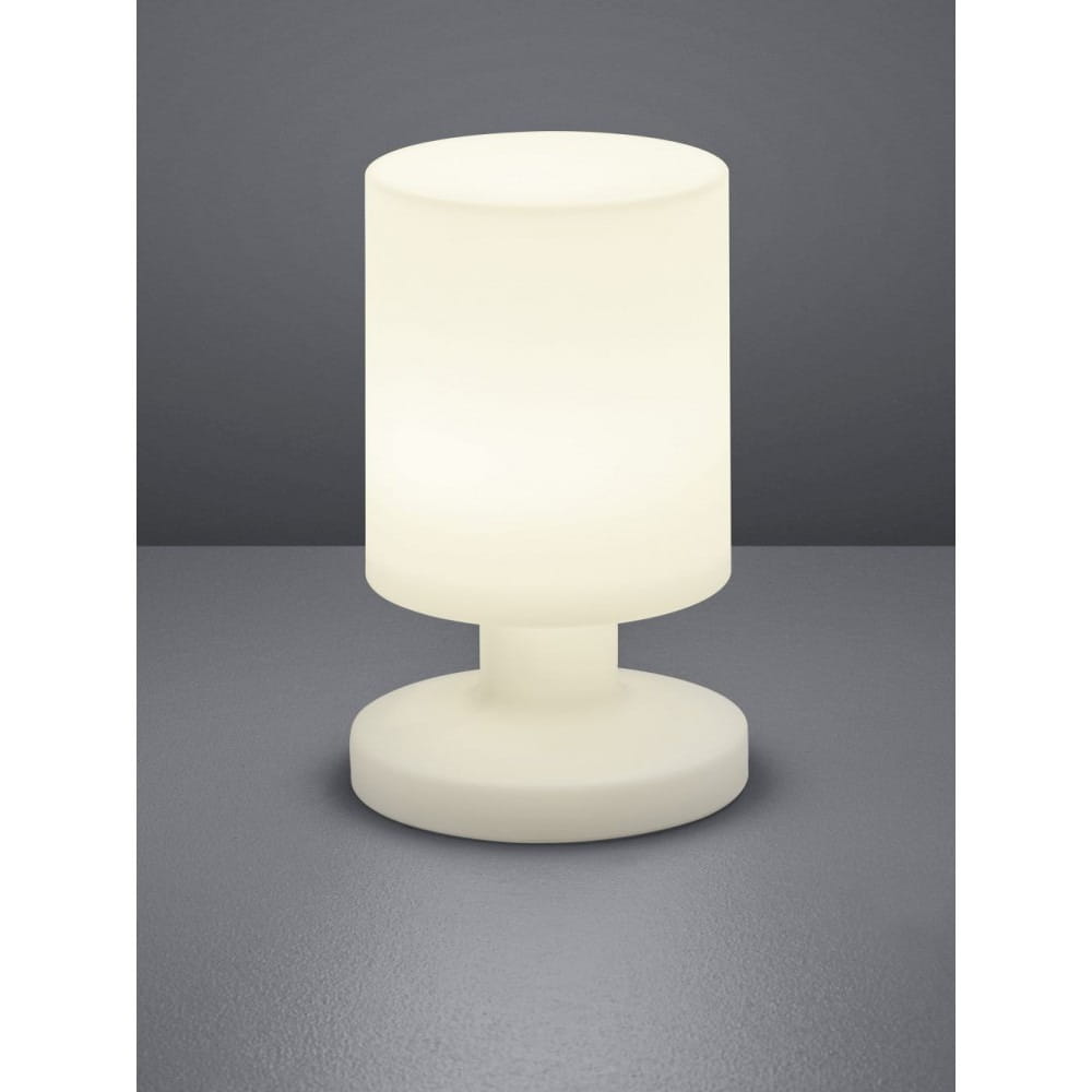 Lora LED lampa stołowa ogrodowa w białym kolorze, z cylindrycznym kloszem i okrągłą podstawą. Ujęcie frontalne, lampa leży na szarej powierzchni, emituje miękkie światło, idealna do użytku na zewnątrz.