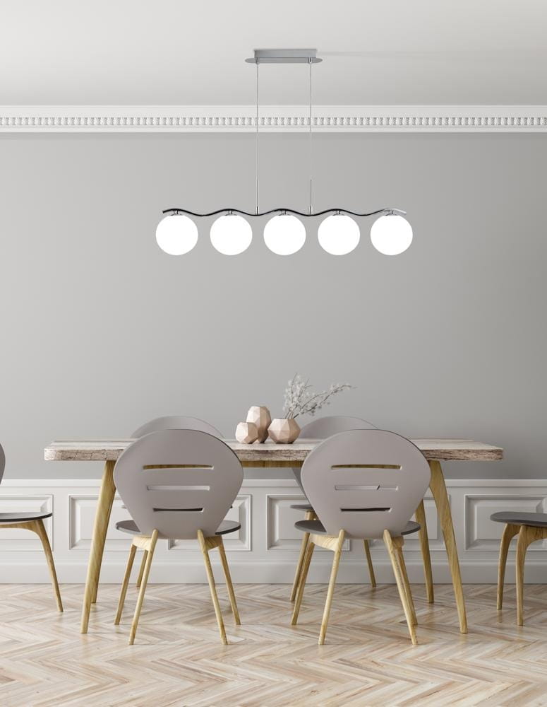 Lampa wisząca Ramon 5-punktowa w wykończeniu chromowym. Zawieszona na cienkich kablach, z pięcioma okrągłymi kloszami w białym kolorze. Umieszczona nad drewnianym stołem w nowoczesnej jadalni, z szarymi krzesłami i minimalistycznymi dekoracjami.