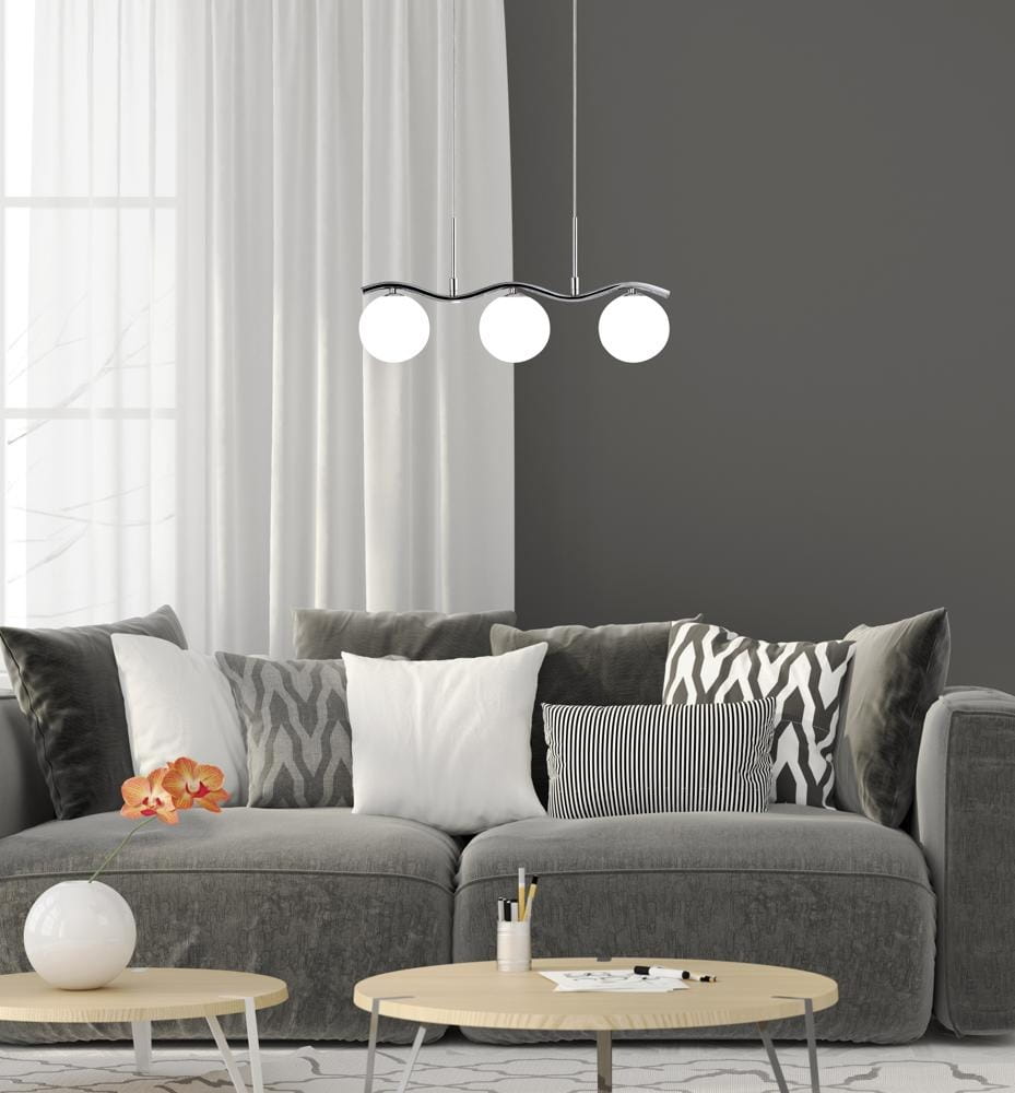 Lampa wisząca Ramon 3-punktowa w chromowanej obudowie z trzema białymi, okrągłymi kloszami. Zawieszona nad szarym sofą z poduszkami, w nowoczesnym wnętrzu z szarymi ścianami i jasnymi zasłonami.