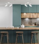 Biała lampa sufitowa Colly z dwoma punktami świetlnymi, montowana na suficie. Lampa umieszczona w nowoczesnej kuchni na tle zielonych szafek i drewnianego blatu. Ruchome reflektory skierowane w dół, o prostym, minimalistycznym designie.