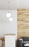 Lampa wisząca Oden D15 w chromowanej oprawie, z dużą, białą kulą szklana. Zawieszona na cienkim przewodzie, w nowoczesnym wnętrzu z drewnianą ścianą i jasnym blatem. Idealna do oświetlenia przestrzeni.