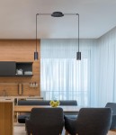 Lampa wisząca Puerto 2-punktowa w kolorze czarnym, z dwoma cylindrycznymi kloszami, zawieszona na cienkich linkach z sufitu. Ujęcie z boku w nowoczesnej kuchni z drewnianymi elementami i jasnymi zasłonami.