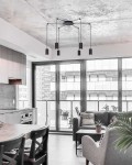 Lampa wisząca Puerto 6-punktowa w kolorze czarnym, z sześcioma cylindrycznymi kloszami, zawieszona na cienkich linkach. Montaż sufitowy w nowoczesnym wnętrzu z widokiem na dużą przeszkloną ścianę.