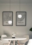 Lampa wisząca Savoy D16 w kolorze czarnym, z okrągłym kloszem w białym kolorze, zawieszona na cienkim przewodzie. Ujęcie frontalne, lampa w nowoczesnym wnętrzu z mapami w ramkach na ścianie oraz okrągłym stołem i rośliną.
