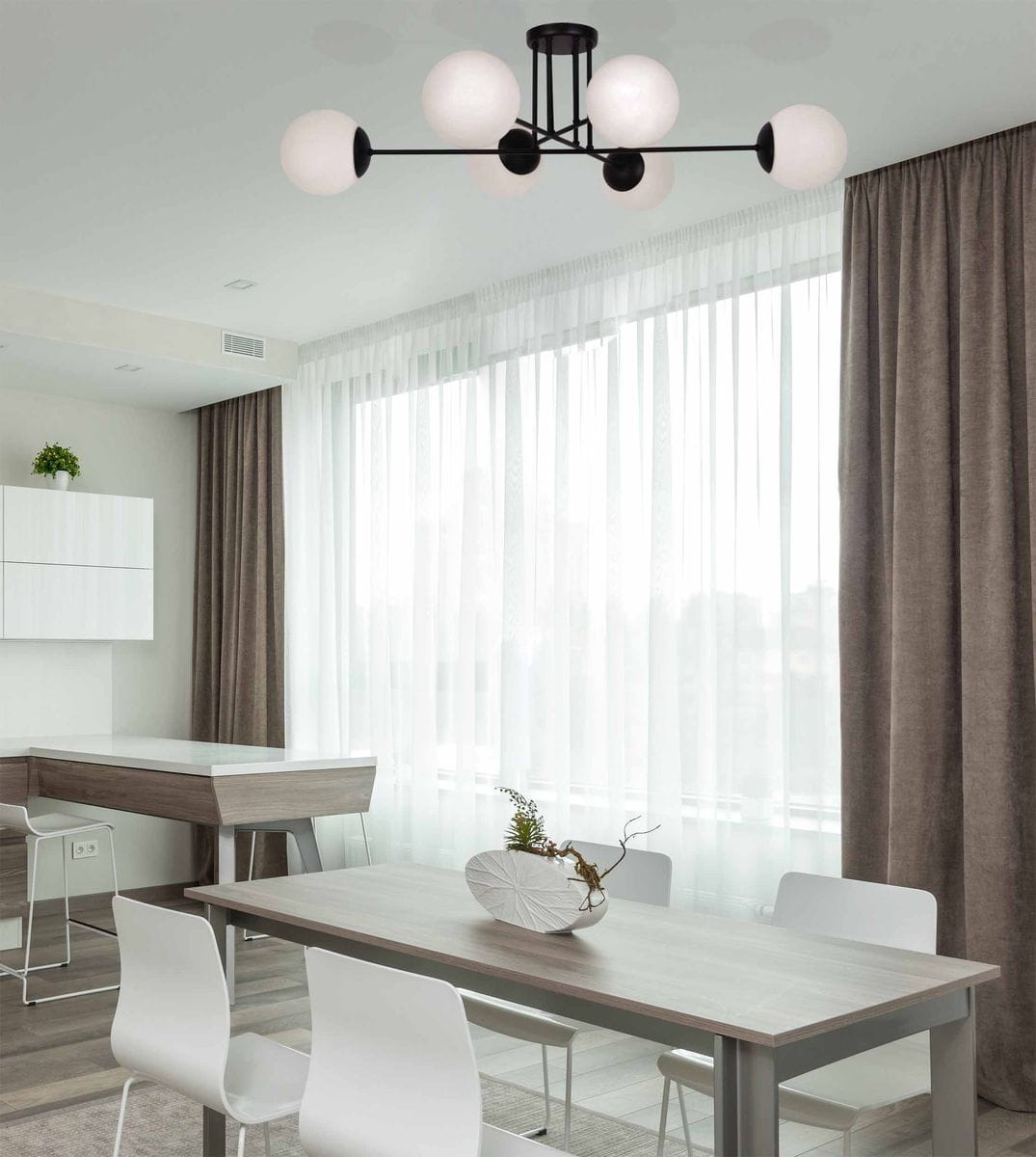 Czarna lampa sufitowa Savoy K-4925 z sześcioma okrągłymi kloszami w białym kolorze, zawieszona na czarnym stelażu. Ujęcie z dołu, w nowoczesnym wnętrzu z jasnymi zasłonami i drewnianym stołem.