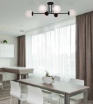 Czarna lampa sufitowa Savoy K-4925 z sześcioma okrągłymi kloszami w białym kolorze, zawieszona na czarnym stelażu. Ujęcie z dołu, w nowoczesnym wnętrzu z jasnymi zasłonami i drewnianym stołem.