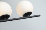 Czarna lampa wisząca Santander z czterema punktami świetlnymi. Okrągłe klosze w opalowym kolorze, umieszczone na poziomej, matowej rurze. Ujęcie z góry, pokazujące szczegóły mocowania i kształt kloszy.