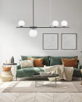Lampa wisząca Santander 4-punktowa w kolorze czarnym z białymi kulistymi kloszami. Zawieszona na długich prętach, w aranżacji nad zieloną sofą z poduszkami. Tło w jasnych odcieniach, minimalistyczne ramki na ścianie.