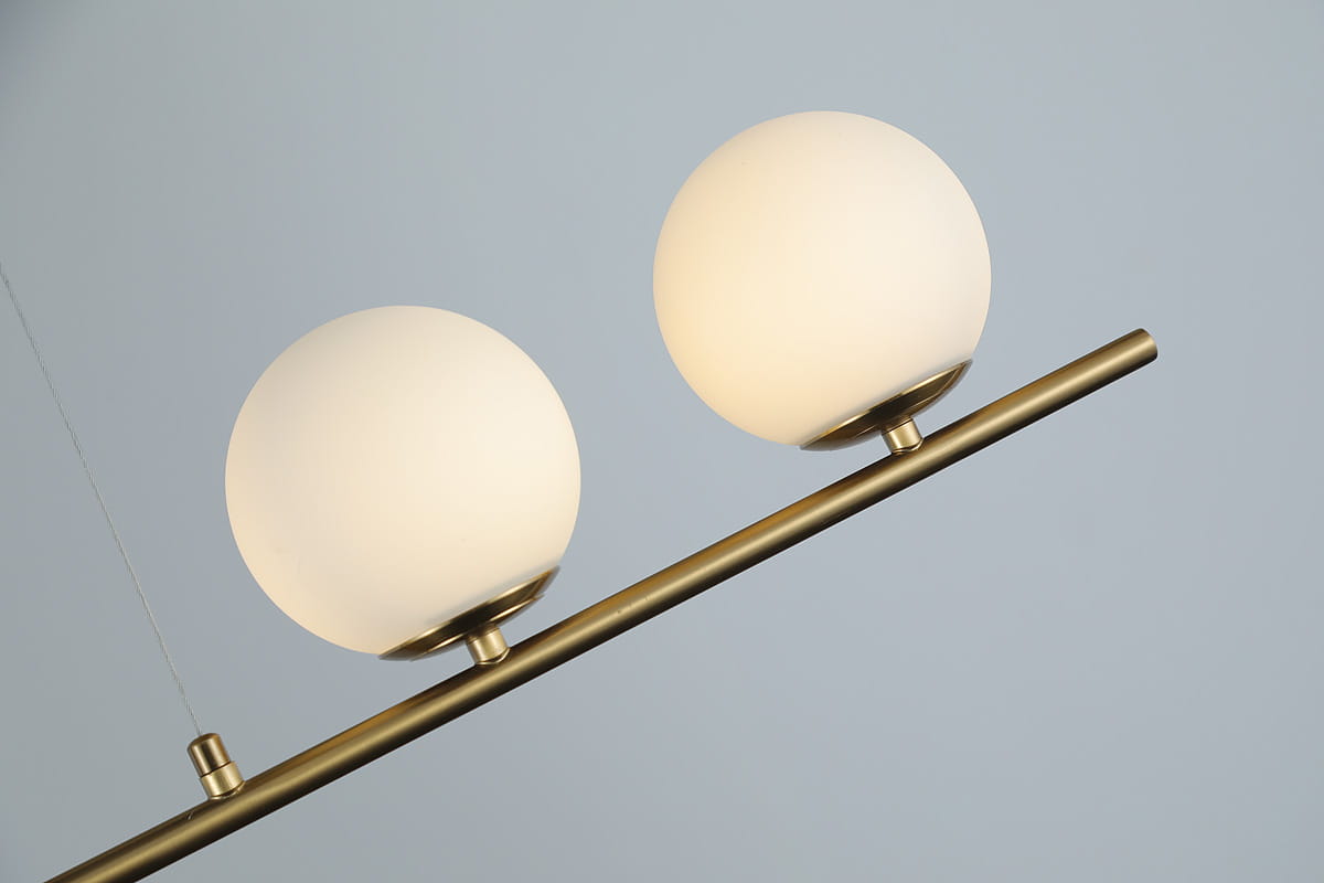 Lampa wisząca Santander 4-punktowa w kolorze złotym, z białymi, okrągłymi kloszami z matowego szkła. Produkt zawieszony na cienkim metalowym drążku, widok z boku. Idealna do nowoczesnych wnętrz.