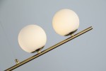 Lampa wisząca Santander 4-punktowa w kolorze złotym, z białymi, okrągłymi kloszami z matowego szkła. Produkt zawieszony na cienkim metalowym drążku, widok z boku. Idealna do nowoczesnych wnętrz.
