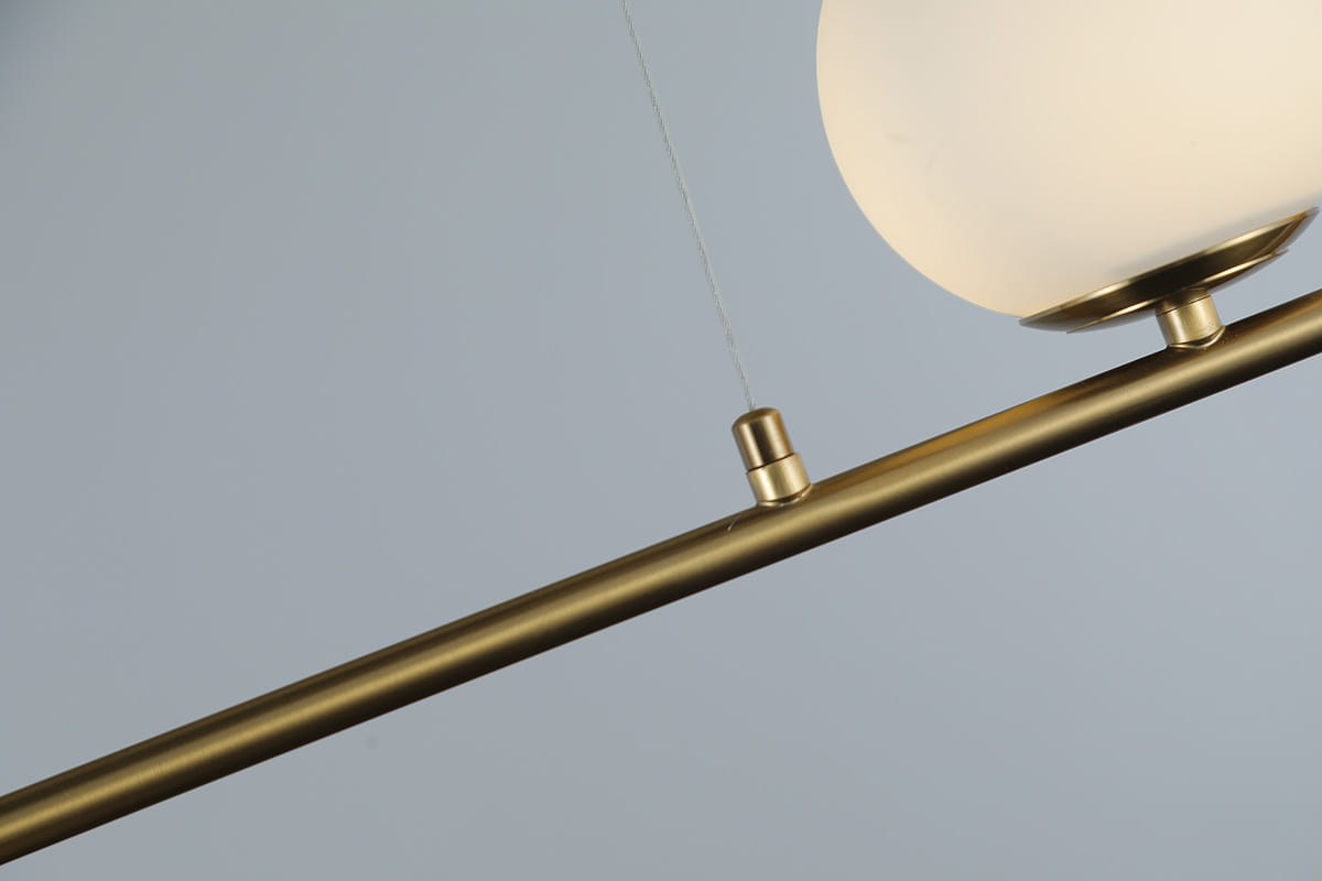 Lampa wisząca Santander 4-punktowa w kolorze złotym. Konstrukcja z metalowego stelaża z okrągłymi oprawami na białe klosze. Ujęcie z góry, pokazujące detale mocowania oraz jedną z lamp. Tło jasnoszare, minimalistyczne.