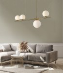 Lampa wisząca Santander 4-punktowa w kolorze złotym, z trzema szklanymi kulami o białej barwie, zawieszona na cienkim, prostym stelażu. Produkt umieszczony nad sofą w nowoczesnym wnętrzu, na tle jasnej ściany.