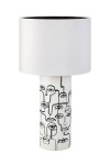 Biała lampa stołowa z 1 punktem świetlnym, okrągły klosz z matowego materiału, cylindryczna podstawa z grafiką twarzy w czarnych konturach. Ujęcie frontalne, lampa stoi na płaskiej powierzchni.