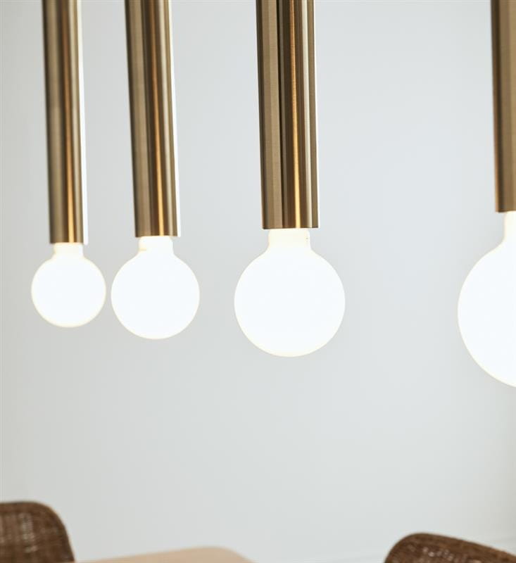Lampa wisząca Sencillo 4-punktowa w kolorze mosiądzu z czterema okrągłymi, białymi żarówkami. Ujęcie z bliska na detal lampy, zawieszonej na prostych, metalowych rurkach. Tło neutralne, podkreślające nowoczesny design.