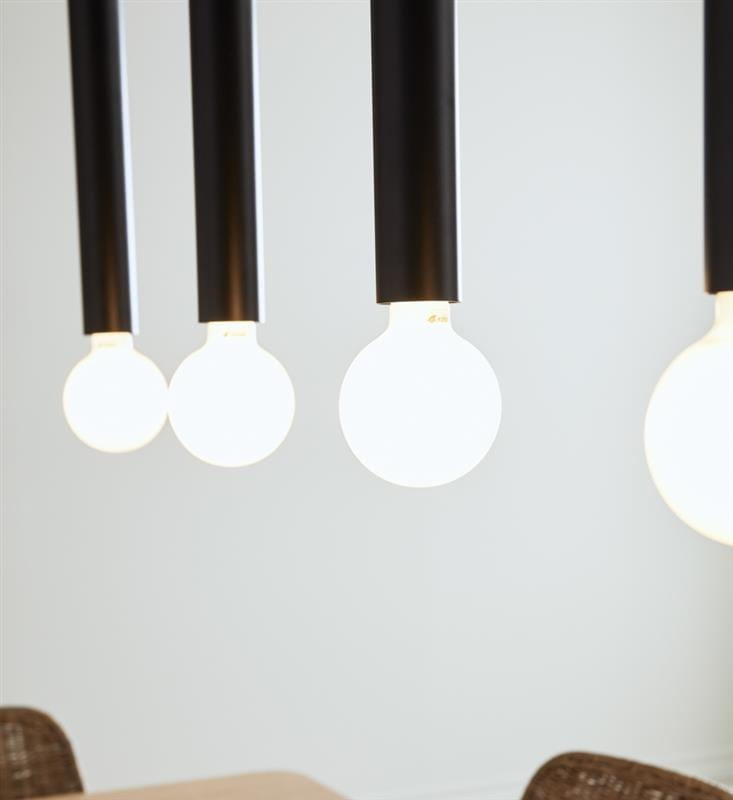 Czarna lampa wisząca Sencillo z czterema punktami świetlnymi. Długie, proste ramiona z matowego metalu, zawieszające białe, okrągłe żarówki. Ujęcie z bliska, na jasnym tle, podkreślające minimalistyczny design i nowoczesny styl.