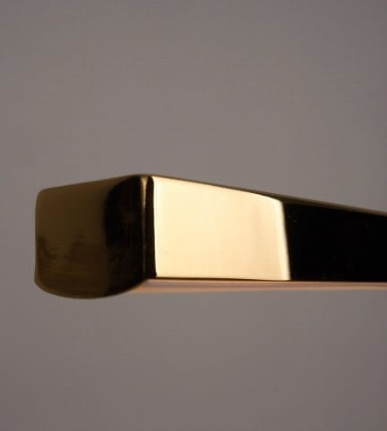 Trio LED lampa wisząca 3-punktowa, złota, z prostokątnymi, błyszczącymi elementami. Ujęcie z boku ukazuje gładką, metaliczną powierzchnię oraz krawędzie. Tło jasne, co podkreśla elegancki wygląd lampy.