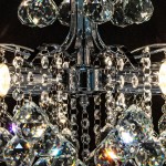Żyrandol Monte Carlo 3-punktowy w kolorze chromu. Ujęcie z góry, z widocznymi kryształowymi elementami w kształcie diamentów oraz błyszczącymi łańcuszkami. Dwa źródła światła oraz eleganckie detale podkreślające nowoczesny design.