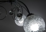Lampa sufitowa Carmen 3-punktowa w kolorze chromu. Posiada okrągłe klosze z teksturowanego szkła, ozdobione kryształkami. Ujęcie z góry, ukazujące dwa klosze i dekoracyjne elementy. Idealna do nowoczesnych wnętrz.