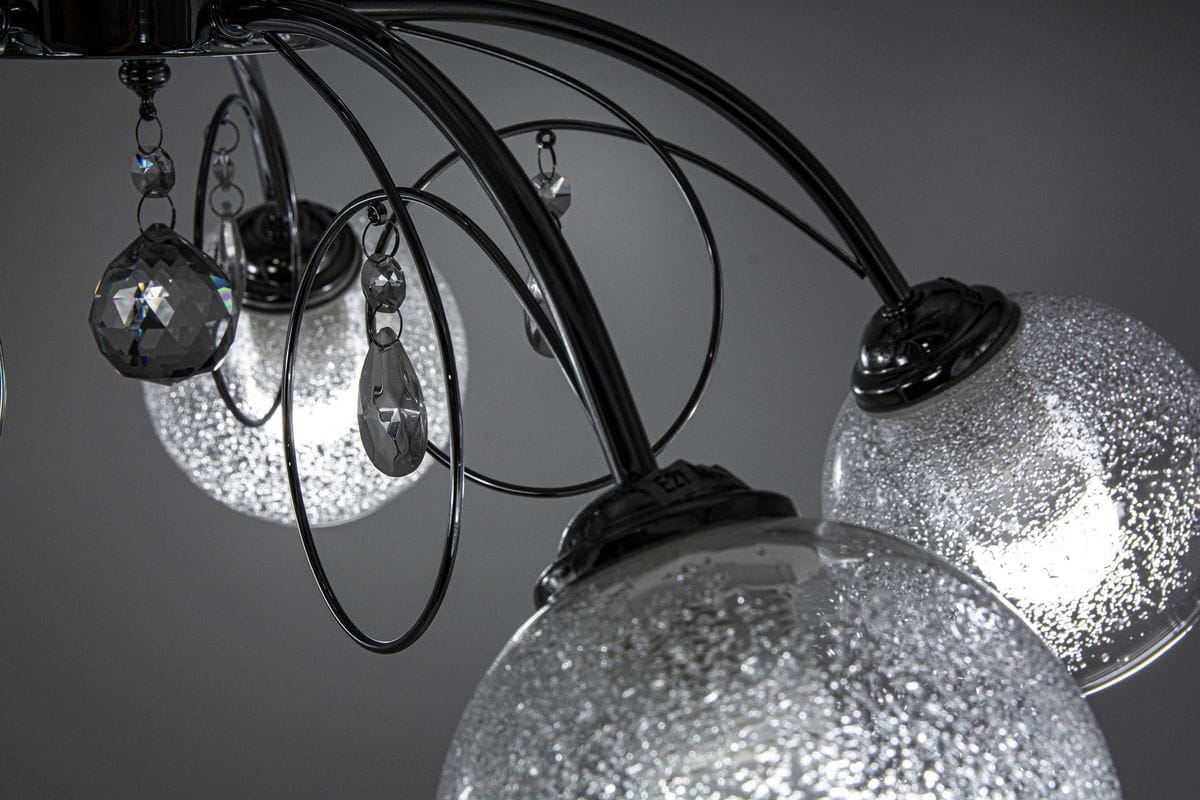 Lampa sufitowa Carmen, 5-punktowa, w chromowanej obudowie. Szklane klosze z fakturą przypominającą bąbelki, dekoracje z kryształkami. Ujęcie z góry, ukazujące szczegóły mocowania i zawieszenia. Tło neutralne, podkreślające elegancję lampy.