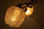 Lampa sufitowa 3-punktowa w kolorze patyny, z trzema kulistymi kloszami w złotym odcieniu o fakturze szkła z brokatem. Klosze umieszczone na metalowej konstrukcji, z dekoracyjnymi elementami kryształowymi.