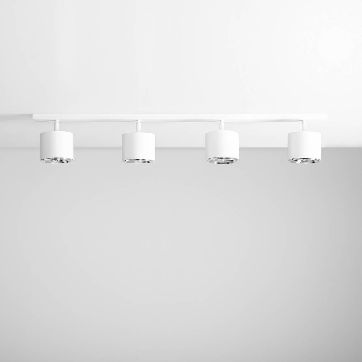 Biała lampa sufitowa 4-punktowa z cylindrycznymi kloszami. Ułożona poziomo, zamontowana na białym panelu. Klosze mają chromowane wnętrza, co podkreśla nowoczesny design. Tło jasne, jednolite, co eksponuje produkt.