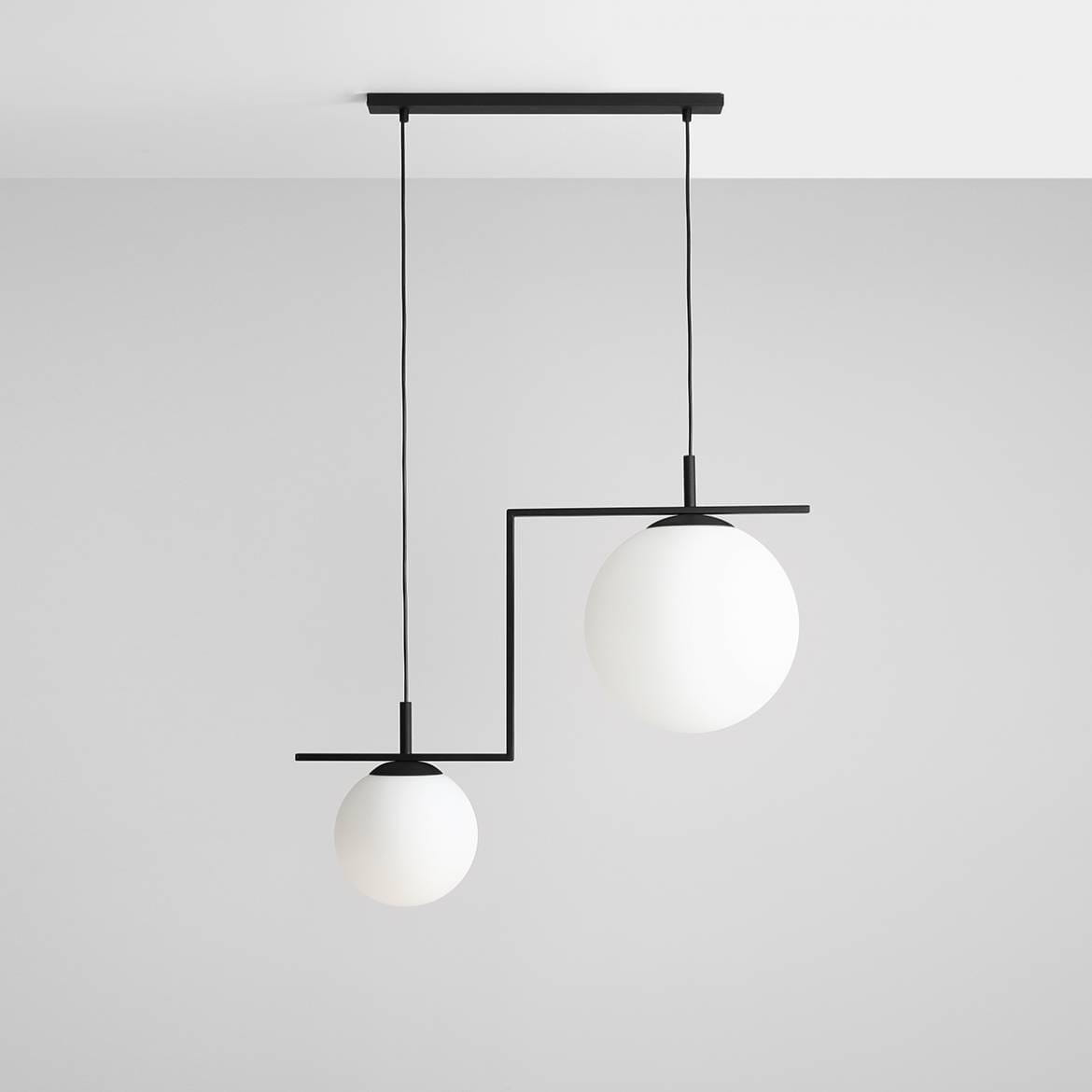 Lampa wisząca Zac II, czarna, z dwiema okrągłymi, białymi kulami na asymetrycznych, metalowych ramionach. Zawieszona na prostokątnej podsufitce, w minimalistycznym stylu, idealna do nowoczesnych wnętrz.