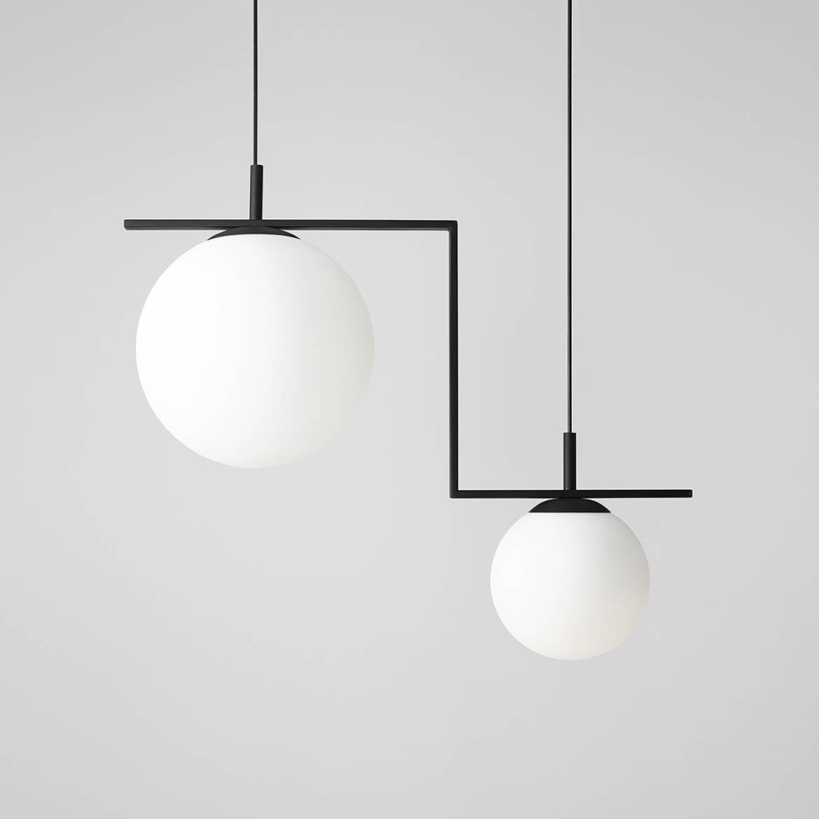 Czarna lampa wisząca Zac II z dwoma punktami świetlnymi, posiadająca okrągłe, matowe klosze w białym kolorze. Lampa zawieszona na cienkich linkach, z unikalnym układem, z większym kloszem po lewej i mniejszym po prawej stronie.