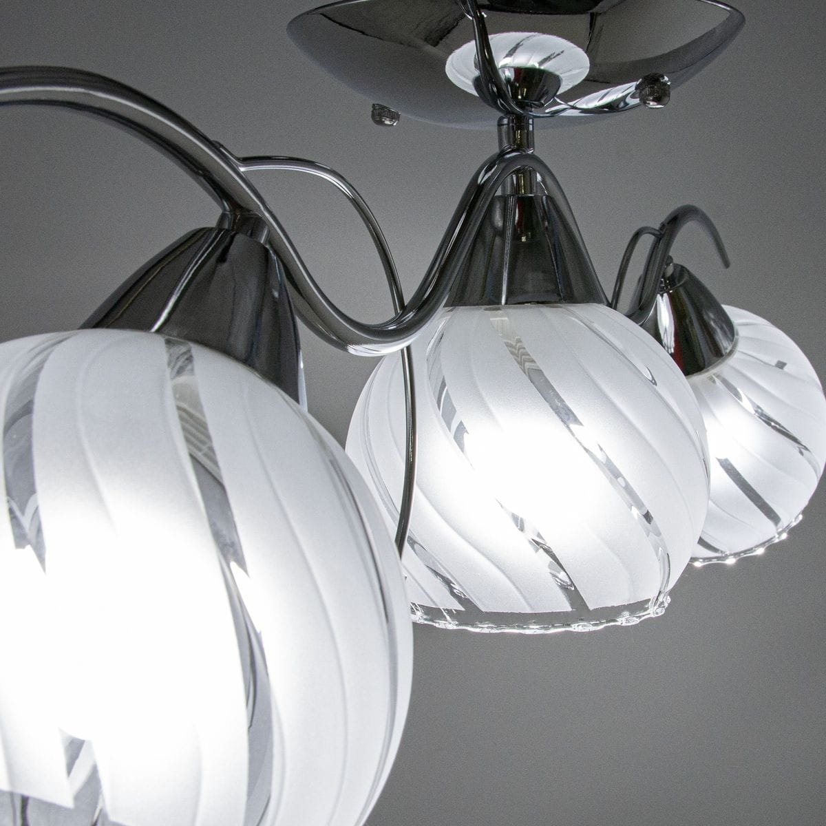 Lampa sufitowa Sting 3-punktowa w chromie, z trzema kulistymi kloszami w białym, matowym szkle z delikatnym, spiralnym wzorem. Klosze są osadzone na eleganckich, chromowanych ramionach, tworząc nowoczesną kompozycję.