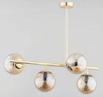 Lungo lampa wisząca 4-punktowa w kolorze złotym, z czterema szklanymi kulami w odcieniu brązowym. Produkt zawieszony na cienkim, złotym stelażu w prostokątnym kształcie, z góry widoczna okrągła podsufitka.