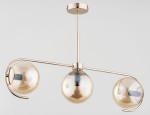 Złota lampa sufitowa 3-punktowa Astana z przezroczystymi kloszami w kształcie kul. Zamontowana na długim, prostym wsporniku, z dekoracyjnym, zakrzywionym uchwytem. Widoczne miejsce na żarówki w każdej kuli. Na jasnym tle.