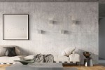 Kinkiet Leo Beton 1-punktowy SL.0991 w kolorze szarym, prostokątny, zamontowany na ścianie z betonu. Produkt znajduje się w aranżacji z jasną sofą i drewnianą podłogą, na tle minimalistycznego wnętrza z obrazem.