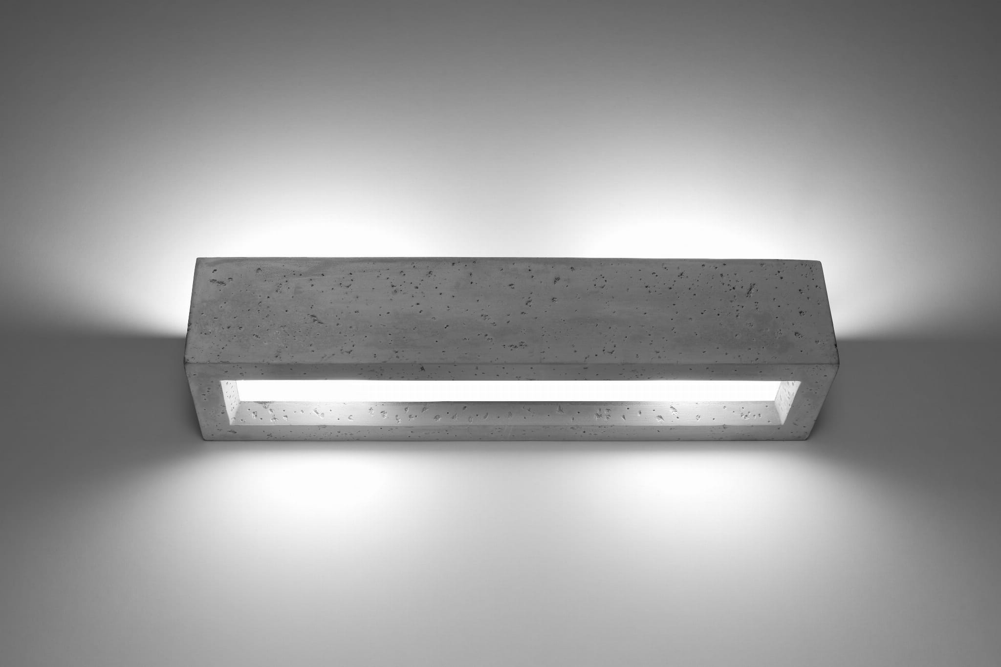 Vega kinkiet 2-punktowy w szarym betonie, prostokątny, z wbudowanym źródłem światła. Montowany na ścianie, o minimalistycznym designie, emituje światło w górę i dół, idealny do nowoczesnych wnętrz. Tło jednolite, jasne.