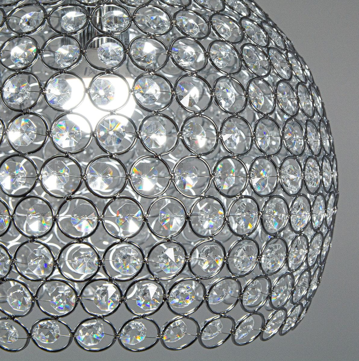 Lampa wisząca Astra 1-punktowa w chromowanej obudowie, z okrągłym kloszem pokrytym lśniącymi kryształkami. Zbliżenie na detal klosza, ukazujące jego przezroczystą fakturę oraz efektowne odbicia światła.