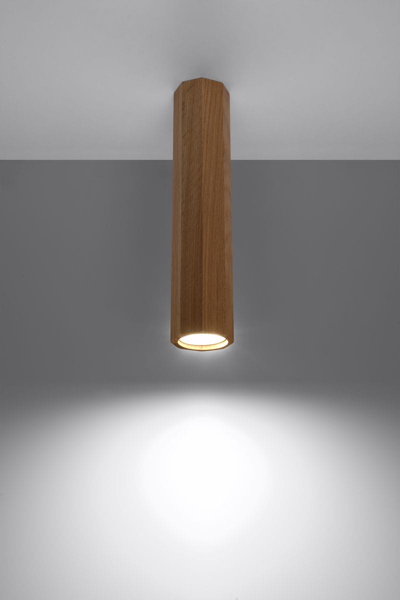 Lampa sufitowa Zeke H30 w kolorze dębu, o cylindrycznym kształcie, zawieszona na suficie. Emituje światło skierowane w dół, na szarym tle. Widoczna jest faktura drewna oraz otwór na żarówkę u dołu lampy.