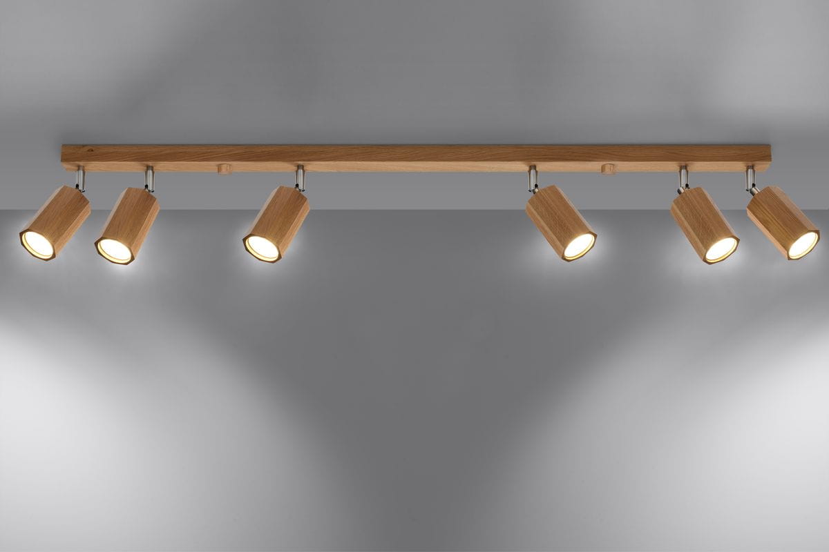 Lampa sufitowa Zeke, 6-punktowa, z drewnianym kloszem, zamontowana na prostokątnej belce. Klosze skierowane w różne strony, emitujące ciepłe światło. Tło szare, minimalistyczne.