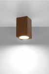 Lampa sufitowa Keke H10 w kolorze dębu, o prostokątnym kształcie, zamontowana na suficie. Emituje światło z okrągłego źródła, umieszczone w dolnej części obudowy. Tło jasne, co podkreśla naturalny wygląd drewna.
