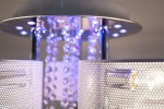 Lampa sufitowa Antila E27 z 22 LED, 3-punktowa, w kolorze chromu z białą siatką. Widoczne dekoracyjne kryształowe elementy oraz podświetlenie LED. Ujęcie z góry, zbliżenie na detale lampy w nowoczesnym stylu.