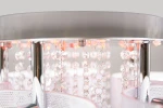 Lampa sufitowa Antila E27 z pięcioma punktami świetlnymi, chromowana z białą siatką. Zbliżenie na detale, w tym przezroczyste kryształy i metalowe elementy. Widoczny pilot do zdalnego sterowania oraz estetyczne wykończenie.