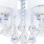 Lampa sufitowa Antila E27 z pięcioma punktami świetlnymi, w kolorze białym i chromowanym, z wiszącymi kryształowymi dekoracjami. Ujęcie z bliska, pokazujące detale kryształów w kształcie piramid oraz plastikowe klosze.