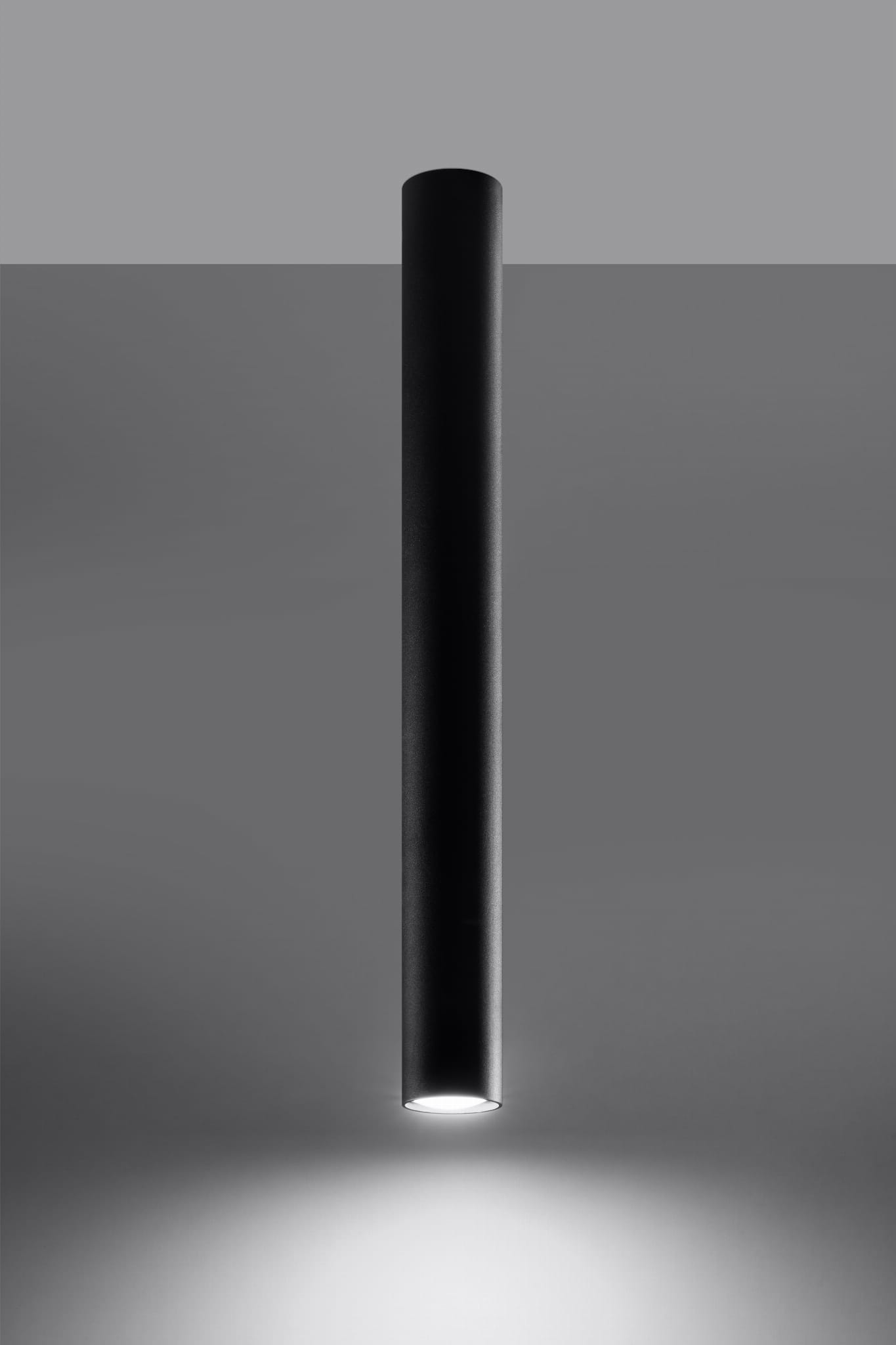 Czarna lampa sufitowa Lagos H60, o cylindrycznym kształcie, zawieszona w pionie. Wykonana z matowego materiału, emitująca światło z dolnej krawędzi. Prosty, nowoczesny design na szarym tle.