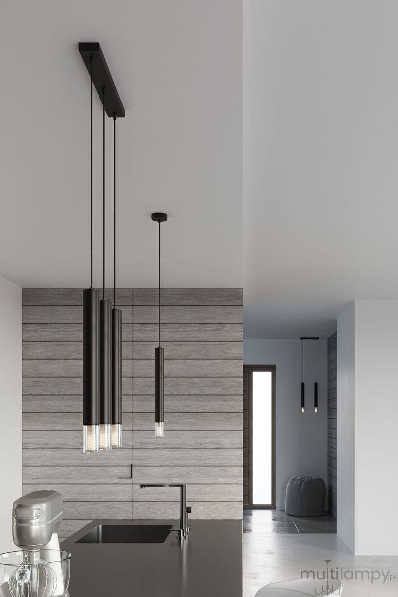 Lampa wisząca Wezyr 2-punktowa w kolorze czarnym, z długimi, cylindrycznymi kloszami. Ujęcie z boku, z widokiem na dwa źródła światła, zawieszona na cienkich linkach. Produkt w nowoczesnej kuchni z drewnianą ścianą w tle.