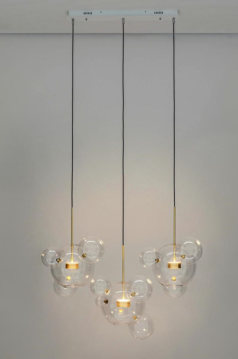 Złota lampa wisząca Capri Line z trzema punktami świetlnymi, zawieszona na czarnych kablach. Szklane klosze w kształcie bąbelków z widocznymi źródłami światła. Prosta, nowoczesna konstrukcja na białym tle.