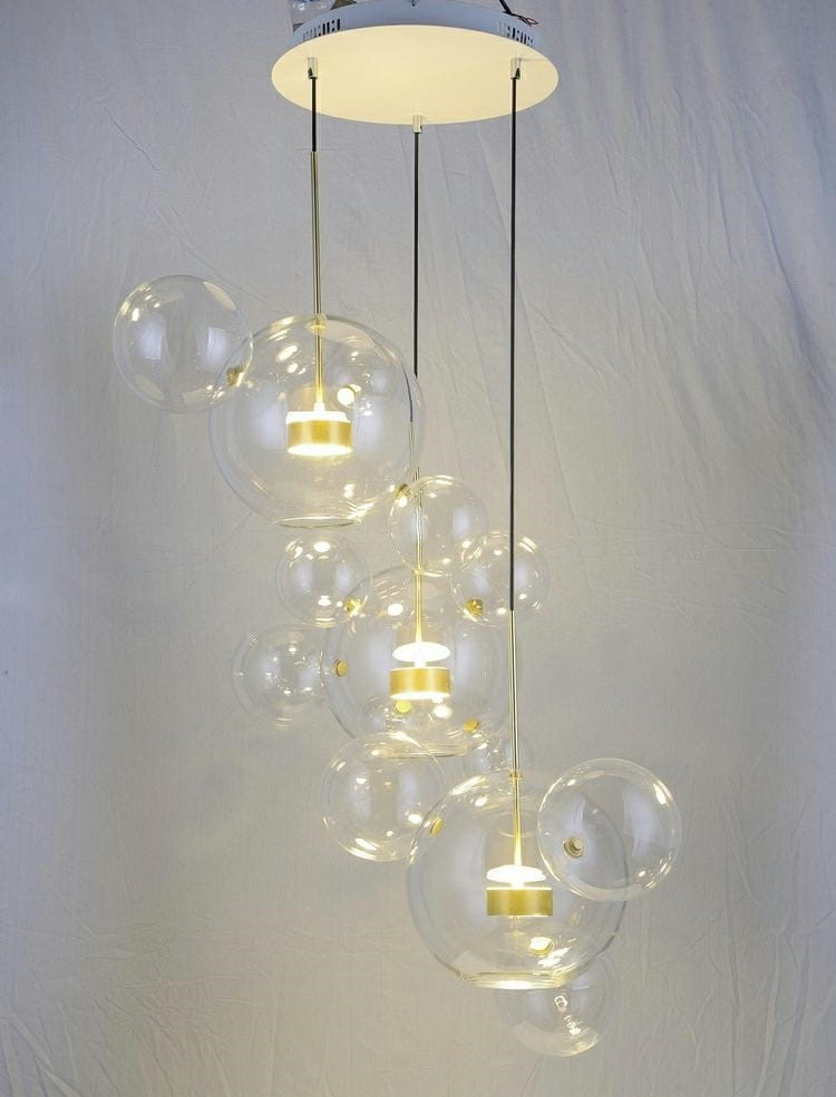 Lampa wisząca Capri Disc LED 3-punktowa w złotym kolorze, z przezroczystymi kloszami w kształcie bąbelków. Lampa zawieszona na cienkich linkach, z centralnym okrągłym mocowaniem sufitowym. Idealna do nowoczesnych wnętrz.