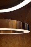 Lampa wisząca Ring D60 LED w złotym kolorze, z okrągłym kształtem i białym podświetleniem. Ujęcie z boku, ukazujące metaliczną teksturę oraz detale konstrukcji. Tło w neutralnym kolorze, eksponujące lampę.