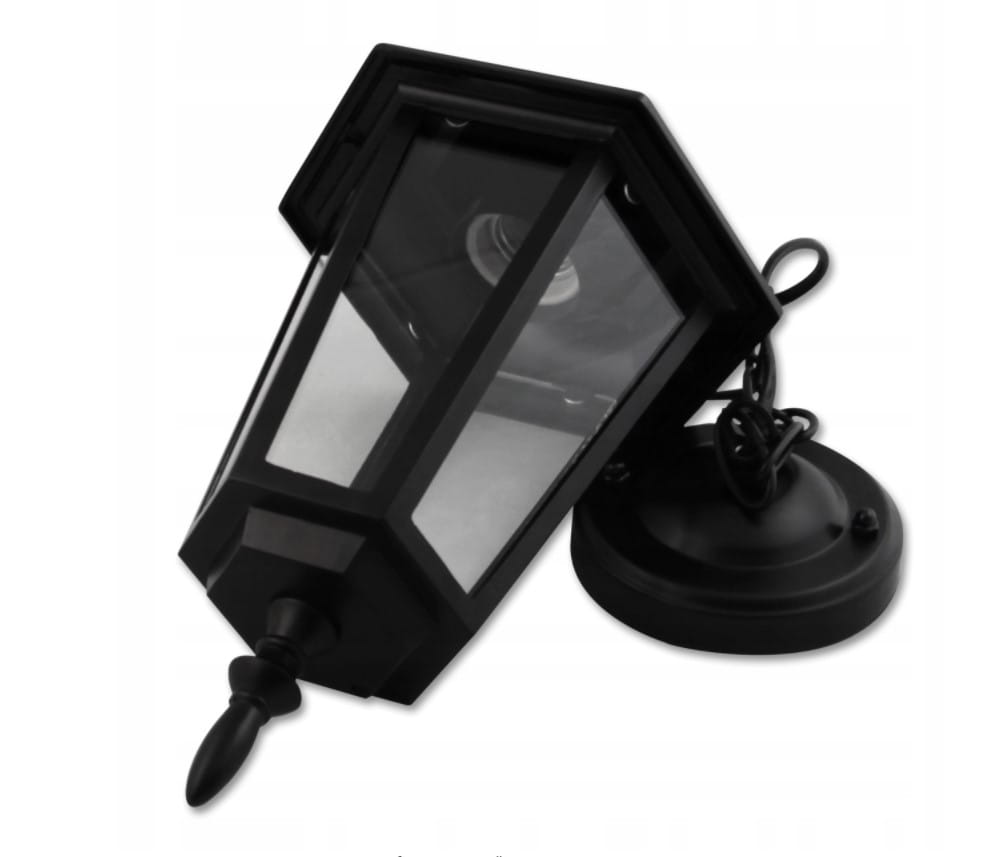 Lampa wisząca ogrodowa Victoria w kolorze czarnym, 1-punktowa. Posiada prostokątny klosz z przezroczystym szkłem i ozdobny uchwyt. Ujęcie z boku, ukazujące detal montażowy na okrągłej podstawie. Idealna do oświetlenia przestrzeni na zewnątrz.