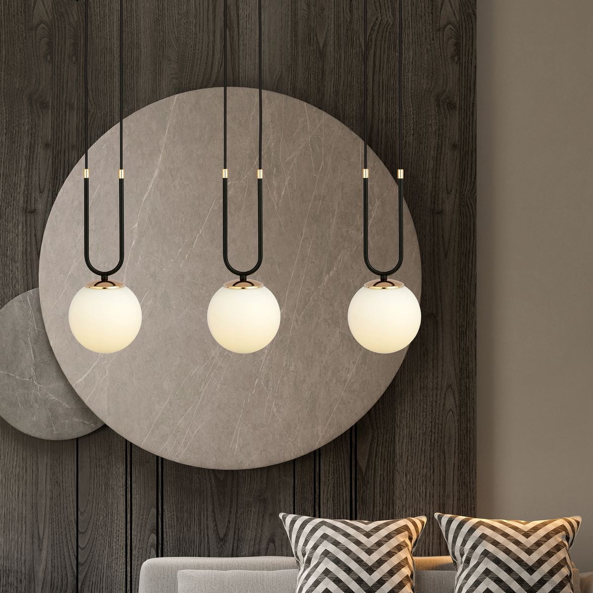 Lampa wisząca Glam 3-punktowa w kolorze czarnym i białym, z trzema okrągłymi kloszami z matowego szkła zawieszonymi na długich, czarnych kablach. Elementy metalowe w kolorze złotym. Tło w odcieniu drewna z dekoracyjnym okrągłym panelem.