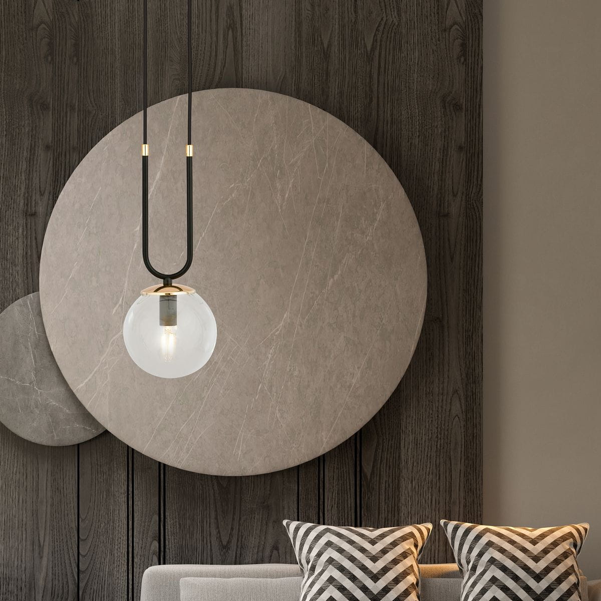 Czarna lampa wisząca 1-punktowa Glam z przezroczystym kloszem w kształcie kuli, zawieszona na dwóch cienkich przewodach. Lampa ma złote detale mocujące. Tło stanowi drewniana ściana z okrągłymi panelami w odcieniach szarości.