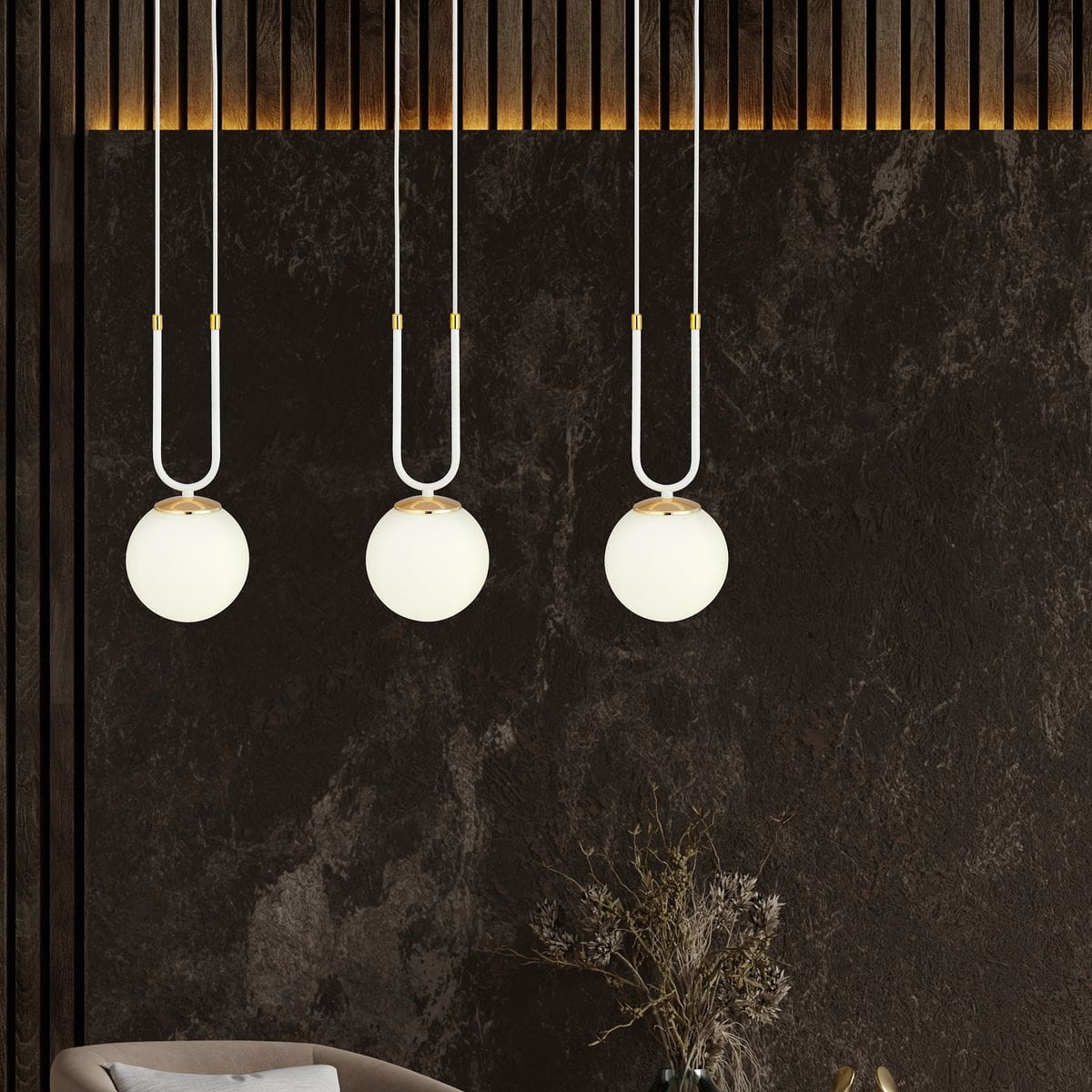 Trzypunktowa lampa wisząca Glam w kolorze białym z okrągłymi kloszami. Klosze zawieszone na białych przewodach z złotymi elementami mocującymi. Lampa umieszczona na tle ciemnej, teksturowanej ściany, w aranżacji wnętrza.