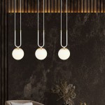Trzypunktowa lampa wisząca Glam w kolorze białym z okrągłymi kloszami. Klosze zawieszone na białych przewodach z złotymi elementami mocującymi. Lampa umieszczona na tle ciemnej, teksturowanej ściany, w aranżacji wnętrza.