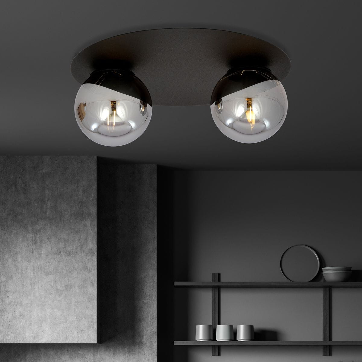 Czarna/grafitowa lampa sufitowa 2-punktowa z dwiema szklanymi, okrągłymi kloszami. Ujęcie z dołu, lampy zamontowane na okrągłej podstawie. Widoczne metalowe detale oraz odbicia światła w kloszach, w tle szare ściany i półki z naczyniami.